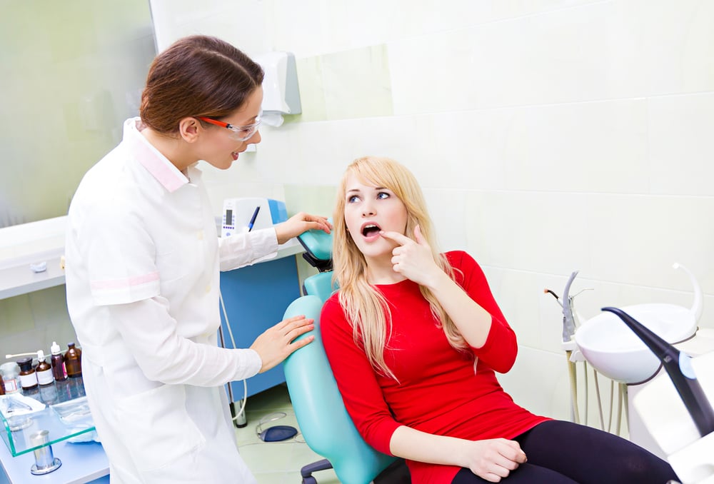Closeup portrait sad girl, patient woman with painful tooth, ache siting in chair, medical office explaining her problem to dentist doctor isolated dental clinic background. Face expressions, feelings-1
