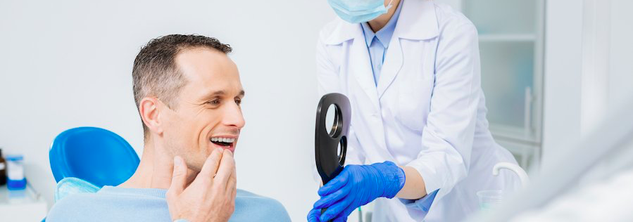 man at dental office admiring new teeth smile