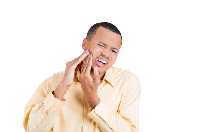 Closeup portrait of young man with tooth ache problem about to cry from pain touching outside mouth with hand, isolated white background, space to right. Negative emotion facial expression feeling