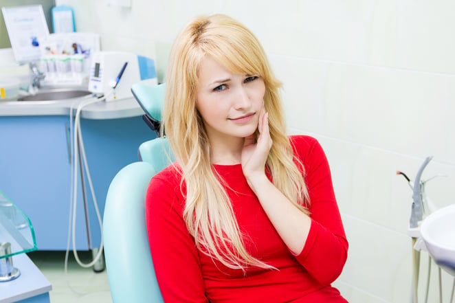 Closeup portrait sad, young girl, woman with painful tooth, ache in medical office siting in chair, isolated dentist clinic office background. Human face expressions, emotions, feelings, reaction-1