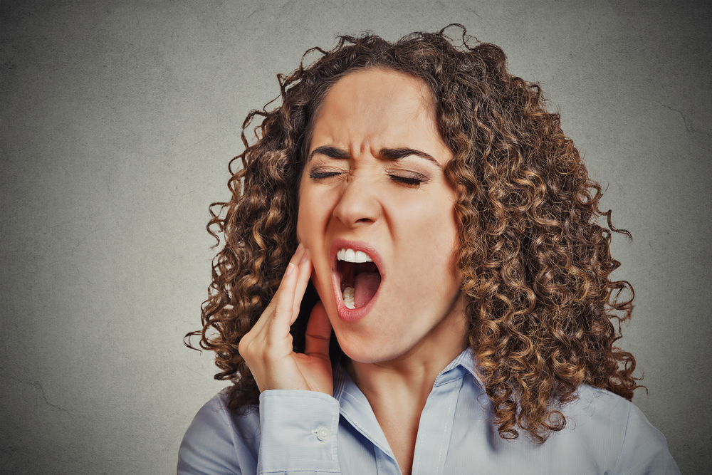 Closeup portrait young woman with sensitive tooth ache crown problem about to cry from pain touching outside mouth with hand isolated grey wall background. Negative emotion facial expression feeling-2