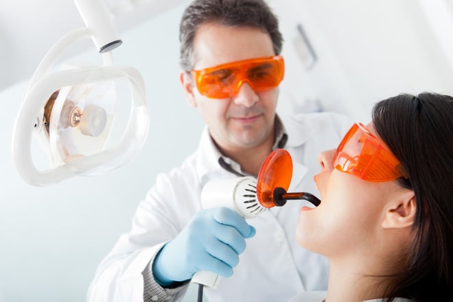 Dentist fixing a cavity on a female patient using laser