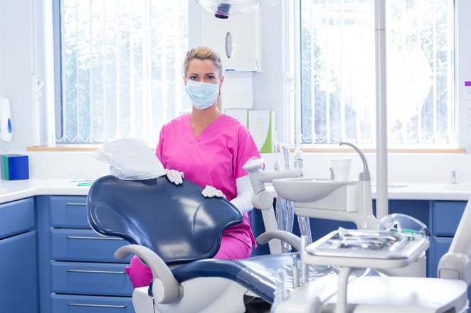 Dentist in mask looking at camera beside chair at the dental clinic-1