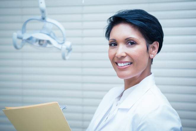 Portrait of smiling female dentist reading reports