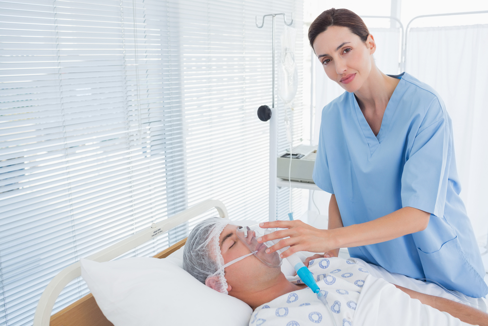 Smiling doctor holding patients oxygen mask in hospital room-2