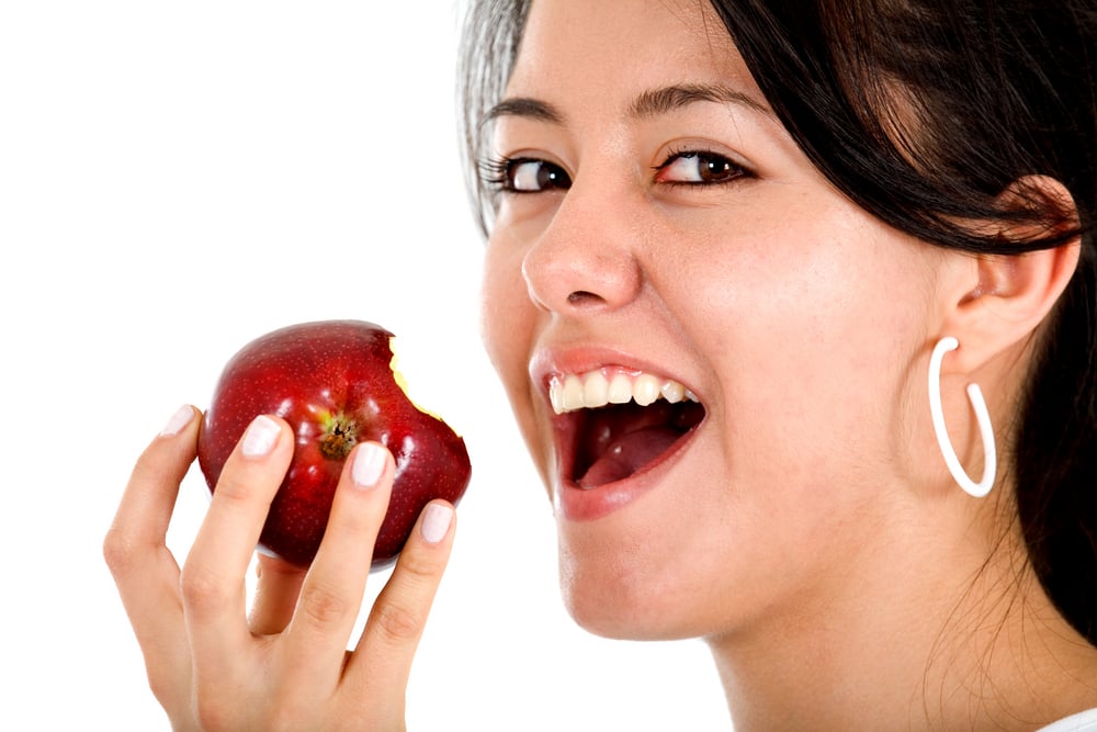 girl eating an apple isolated over a white background